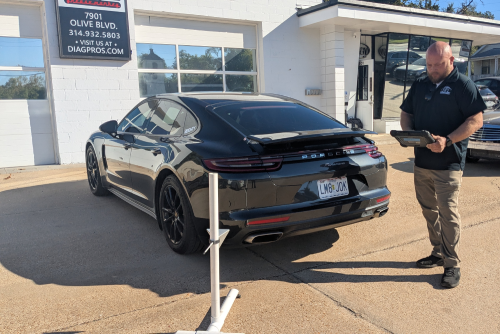 Automobile computer diagnosis. Car mechanic repairer looks for engine failure on diagnostics equipment in vehicle service workshop